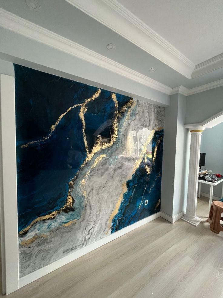 ديكور حائط ببديل الرخام بتصميم عصري بألوان الأزرق والرمادي مع عروق ذهبية، مثبت في صالة منزلية بإطار أبيض