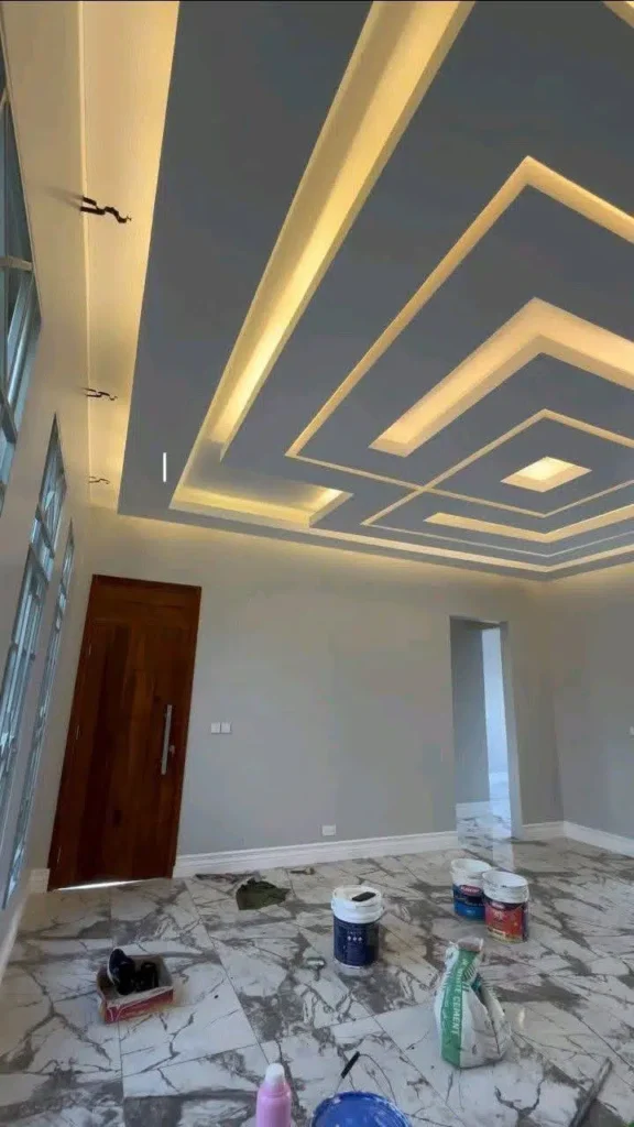 سقف جبس بورد مودرن بإضاءة مخفية LED بتصميم هندسي أنيق داخل غرفة مع تشطيب داخلي حديث وأرضية رخامية قيد التنفيذ